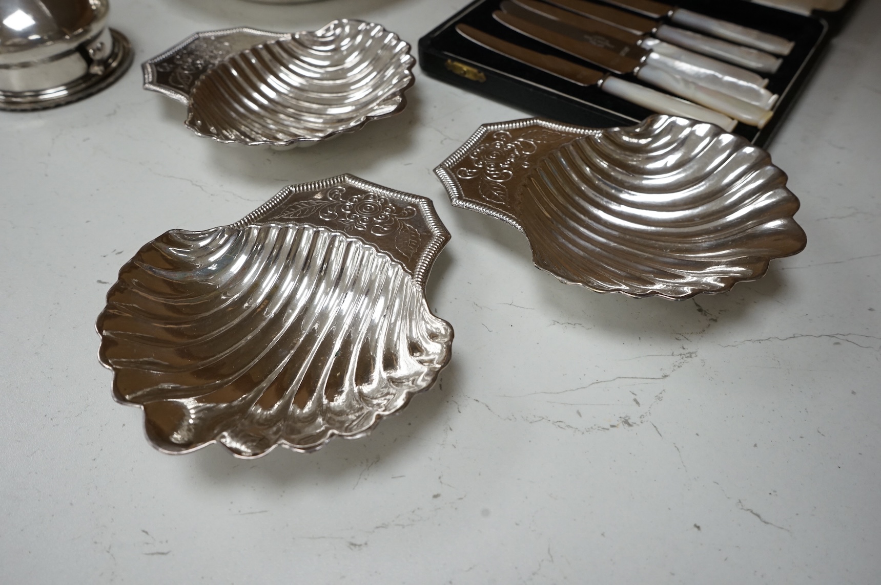 A Mappin plated muffin dish and six other plated items including three Old Sheffield plate butter shells, a wine funnel, Elkington & Co cream jug and cased set of tea knives.